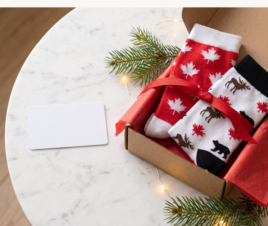 Gift box with moJJa maple leaf and moose socks beside a blank gift card